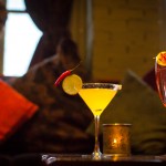 Cocktail glass with yellow drink and slice of lemon