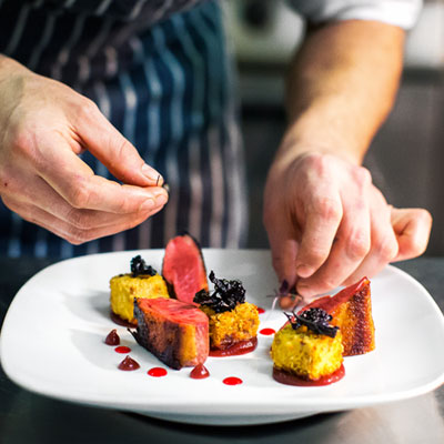 chef preparing food being laid out on a plate in the kitchen