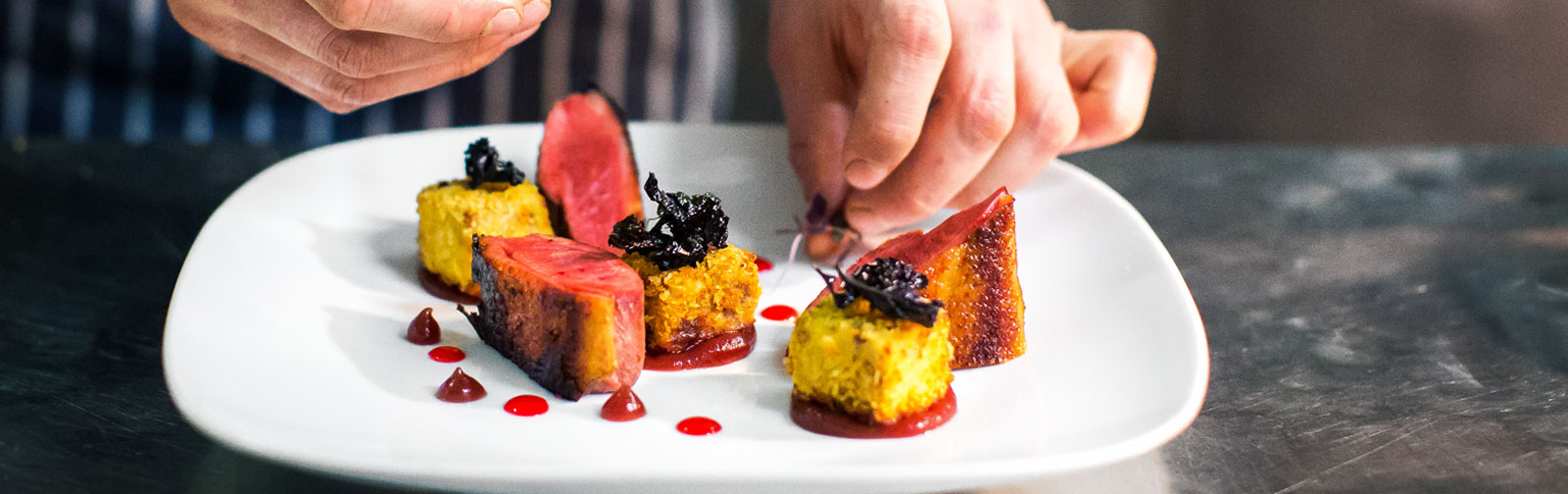 chef preparing food being laid out on a plate in the kitchen